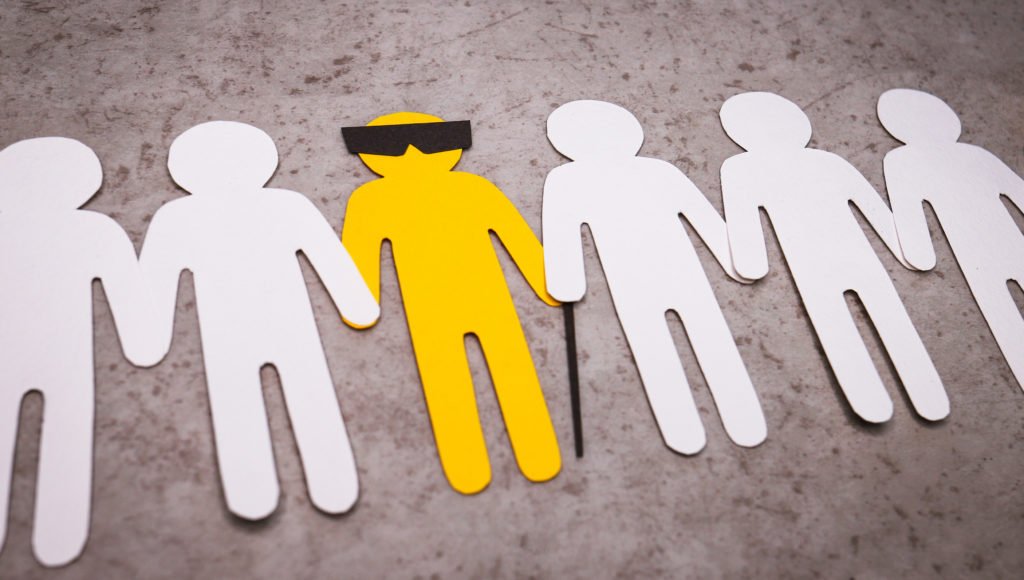 grafika dotycząca osób niewidomych, na beżowym tle białe ikony ludzi trzymają za ręce żółtą postać w czarnych okularach